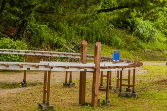Miniature train tracks supported by wooden structures in a park setting, in South Korea