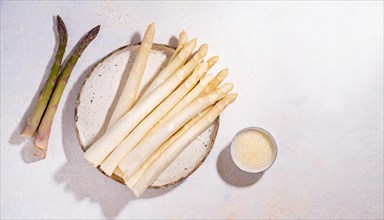 White and green asparagus on a plate with parmesan next to it, presented on wood, AI generated, AI
