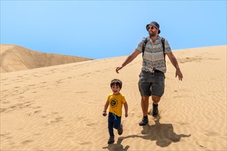 Father and son tourists enjoying in the dunes of Maspalomas, Gran Canaria, Canary Islands