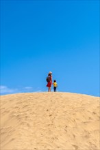 Mother and child smiling in the dunes of Maspalomas in summer, Gran Canaria, Canary Islands
