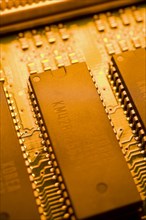 Close-up of orange yellow lighted electronic computer circuit board with memory chips and silver