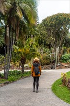A woman enjoying and walking in a tropical botanical garden with palm trees