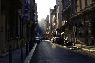 Marseille in the morning, city street with sunlit and shaded areas and parked cars, Marseille,