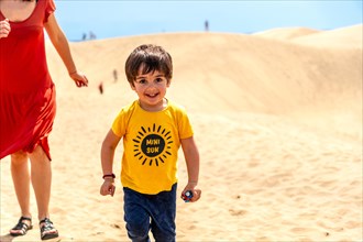 Mother and son on vacation smiling in the dunes of Maspalomas, Gran Canaria, Canary Islands