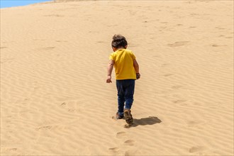 Tourist boy walking in the dunes of Maspalomas, Gran Canaria, Canary Islands