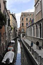 Canal in Venice with boats, surrounded by historic buildings and people walking, Venice, Veneto,