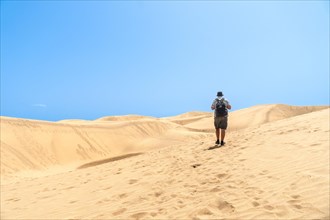 A tourist walking through the dunes of Maspalomas, Gran Canaria, Canary Islands