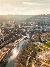 Aerial view of a city panorama with river and sun reflections next to urban architecture, sunrise,