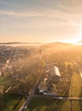 A town awakes in the light of sunrise, shrouded in light fog, Gechingen, Black Forest, Germany,