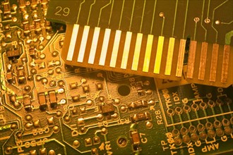 Close-up of golden yellow lighted green electronic computer circuit boards with silver solder