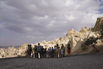 Tourists visiting the rock-cut cave dwellings in Goreme valley, Cappadocia region, Turkey, Asia