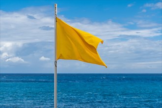 Yellow flag on the beach in summer summer, lifeguards sign to bathe carefully
