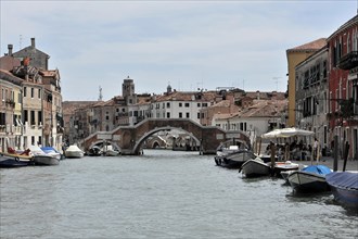 Boats lying on the banks of a Venetian canal under a stone bridge, Venice, Veneto, Italy, Europe
