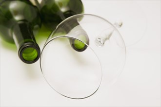 Close-up of two consumed and empty green glass bottles of red wine with tilted wine glass on white