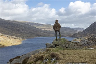Woman standing on stone, Lake Llyn Ogwen, Snowdonia National Park near Pont Pen-y-benglog,