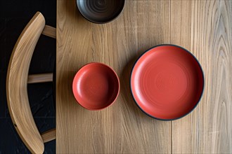 Minimalist table setting featuring red bowls with circular patterns on a wooden surface, AI