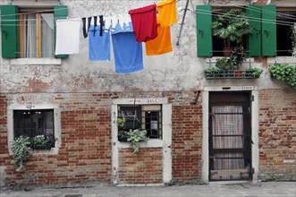 Colourful laundry hanging on a washing line in front of old Venetian house facades, Venice, Veneto,