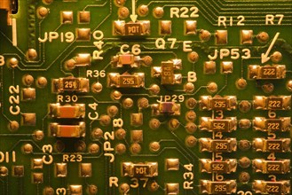 Close-up of golden yellow lighted green electronic computer circuit board with lines and silver
