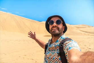 Selfie of a tourist with glasses and hat enjoying in the dunes of Maspalomas, Gran Canaria, Canary