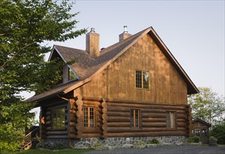 Facade and side view of rustic contemporary Scandinavian hybrid style log cabin home with light