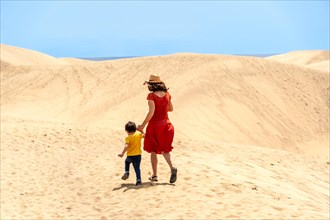 Mother and son on vacation walking in the dunes of Maspalomas, Gran Canaria, Canary Islands