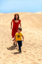 Mother and son tourists on vacation very happy in the dunes of Maspalomas, Gran Canaria, Canary