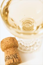 Top view and close-up of filled champagne glass and bottle cork on white background, Studio