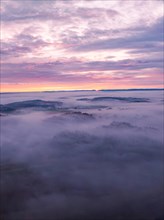 Gentle hills rise out of the fog under pink-coloured clouds, Gechingen, Black Forest, Germany,
