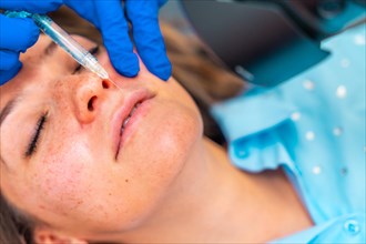 Close-up top view of a woman receiving a botox injection to the lips lying on stretcher in the