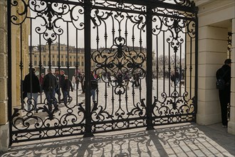 Through an ornate wrought iron gate you can see the forecourt of Schoenbrunn Palace in Vienna with