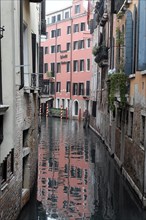 Reflection of a pink building in a quiet Venetian canal, Venice, Veneto, Italy, Europe