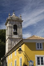 Yellow painted roughcast building and Church bell tower in the village of Sintra, Portugal, Europe