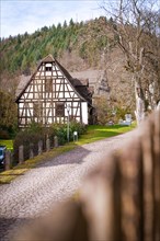 Old half-timbered house on a cobbled street with trees in the background, Calw, Black Forest,