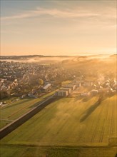The morning sun gently illuminates the foggy landscape around the town, Gechingen, Black Forest,