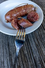 A Plate with Luganighe Sausage with a Fork on a Wood Table with Sunlight in Lugano, Ticino,