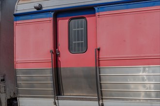 Red and silver train carriage door with metal handles, in South Korea