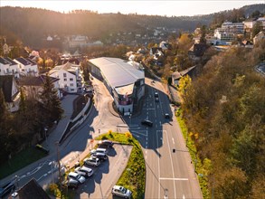 Drone view of a large commercial building surrounded by streets and cars at sunset, Calw, Black