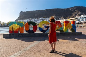 A woman on the tourist sign in the coastal town Mogan in the south of Gran Canaria. Spain