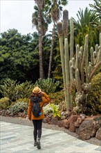 A woman enjoying and walking in a tropical botanical garden with many captus