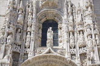 Arched window with decorated carved sculptures on facade of Jeronimos Monastery, Lisbon, Portugal,