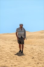Portrait of male tourist in summer walking in the dunes of Maspalomas, Gran Canaria, Canary Islands