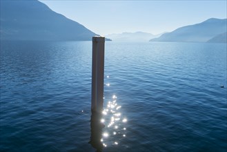 Pole with Sun Reflection on Lake Maggiore with Mountain in Ascona, Ticino, Switzerland, Europe
