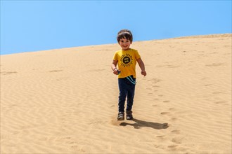 Tourist boy smiling in the dunes of Maspalomas, Gran Canaria, Canary Islands