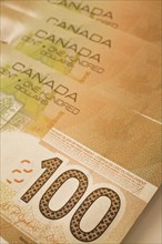 Close-up of brown Canadian Bank of Canada one-hundred dollar bank notes, Studio Composition,