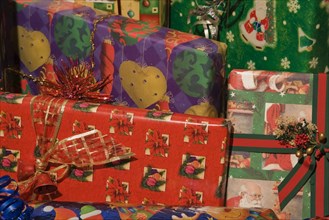 Close-up of boxed Christmas gifts wrapped with colorful red, green, purple and gold wrapping paper,