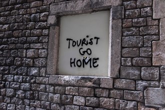 Tourist go home lettering on a wall in Barcelona, Spain, Europe