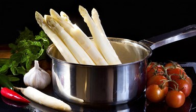 White asparagus spears in a pot next to fresh tomatoes and chilli, fresh white asparagus in a