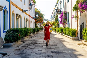 A woman walking in the port of the flower-filled coastal town Mogan in the south of Gran Canaria.