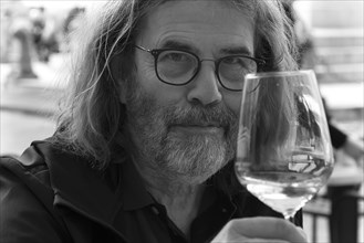 Portrait of a man with a beard and glasses, toasting with a wine glass, Genoa, Italy, Europe