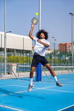 Vertical full length photo of a african american young sportive man jumping to reach the ball